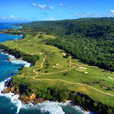 Aerial view of Playa Grande Golf Course at Amanera, with emerald fairways winding through dense forest and turquoise coastline below.