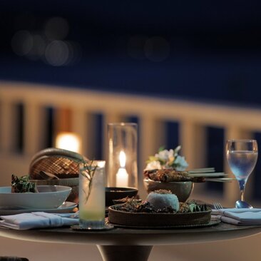 Candlelit dinner table with place settings at Amankila resort, Indonesia, at dusk.