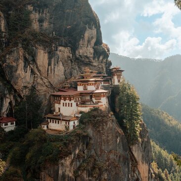 Tiger's Nest monastery clinging to a cliff face in Paro, Bhutan, with mountains beyond.