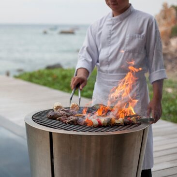 Chef grilling over an open flame at Amanoi's Beach Club restaurant, Vietnam.