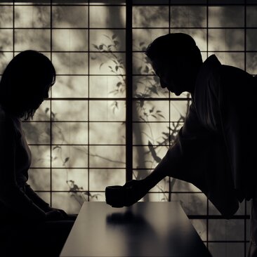 Two people in silhouette at Aman Kyoto, seated at a table beside a latticed window with climbing ivy.