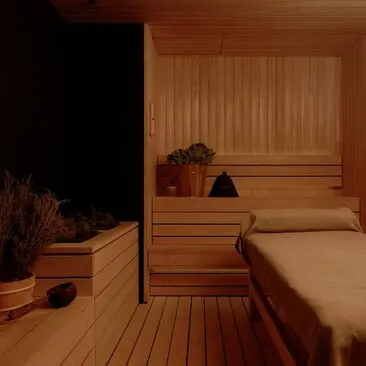Wooden sauna interior at Aman Nai Lert Bangkok with bench seating and warm lighting.