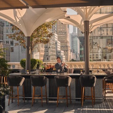 Bartender prepares un cóctel en la terraza del jardín con vistas a la ciudad en Aman New York.