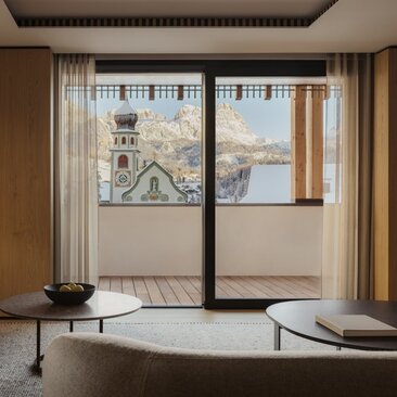Bedroom at Aman Rosa Alpina with framed artwork on glass doors and views across the Italian Alps.