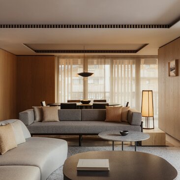 Rosa Alpina Suite living area with neutral furnishings, fireplace and floor-to-ceiling windows overlooking the Dolomites.