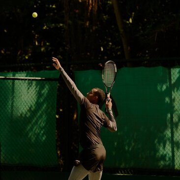 Joueur de tennis en action sur un court illuminé à Amanera, resort en République dominicaine.