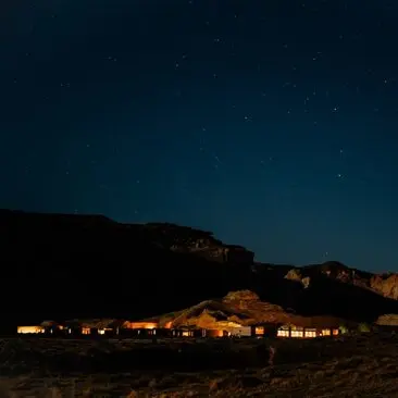 Amangiri glows softly under a starlit desert sky at dusk.