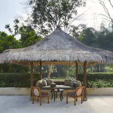 Thatched pavilion with seating area at Amanjiwo resort, surrounded by lush gardens.