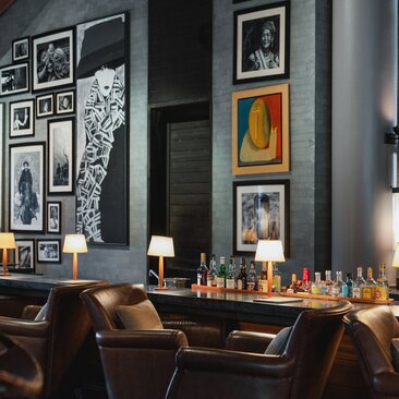 Bar area at Amanoi resort with leather seating, framed artwork and warm lighting.