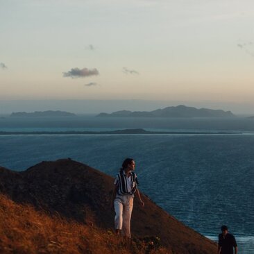 Randonneurs admirant la vue sur l'île de Manamoc depuis un promontoire rocheux à Amanpulo.