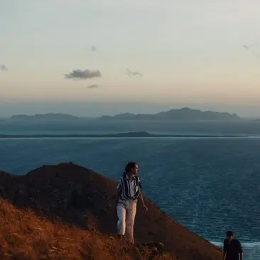 Hikers on Manamoc Island at sunset, overlooking the waters surrounding Amanpulo resort, Philippines.