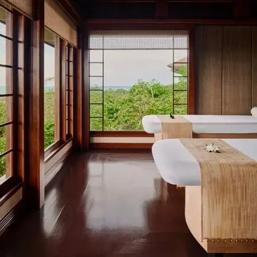 Spa massage room at Amanpulo resort with wooden features, bathtub and views across Philippine landscape.