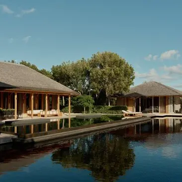 Villa pool at Amanyara overlooking calm water with thatched-roof structures and tropical grounds.