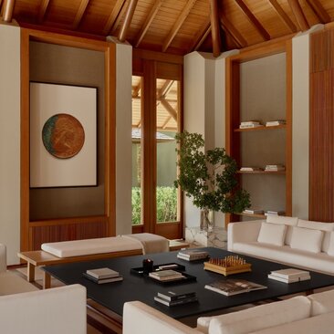 Amanyara villa living area with wooden ceiling, neutral furnishings, and potted plant on black table.