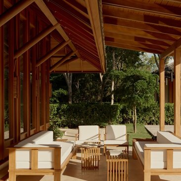 Amanyara villa outside living area with wooden beams, seating and views into tropical gardens.