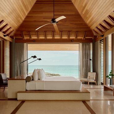 Villa interior at Amanyara with vaulted wooden ceiling, opening onto turquoise Caribbean waters.