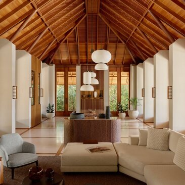 Amanyara villa living area with pitched wooden ceiling, cream seating and tropical views through open doors.