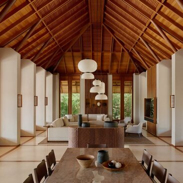 Amanyara villa living area with soaring wooden ceiling, white walls, and minimalist furnishings overlooking tropical gardens.