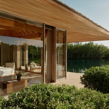 Amanyara villa pavilion with wooden ceiling, open doors, and manicured garden views.