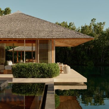 Amanyara villa pavilion with wooden beams overlooking a reflecting pool at dusk.