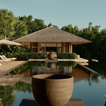 Villa pool exterior at Amanyara, Turks and Caicos, with thatched pavilion and reflecting water.