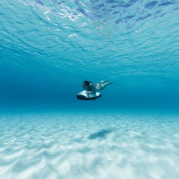 Snorkeller swimming above white sand seabed in clear turquoise waters at Amanyara.