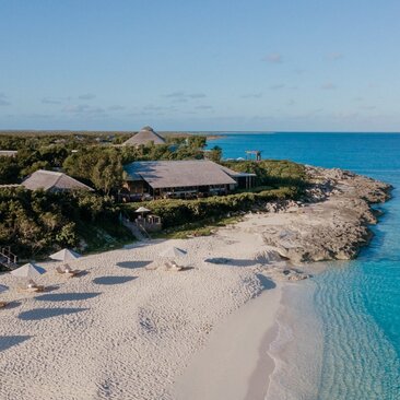 Amanyara's Beach Club nestled on pristine white sand beside turquoise waters in Turks and Caicos.