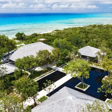 Aerial view of a four-bedroom villa at Amanyara with white pavilions, infinity pool and beach access in Turks and Caicos.