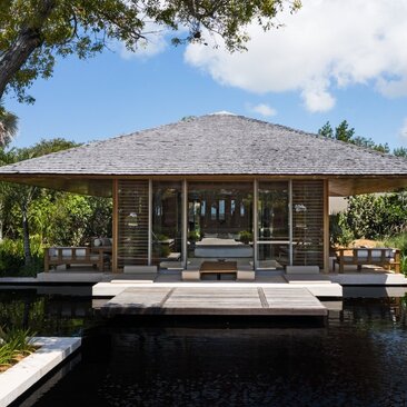 Four-bedroom beachfront sala at Amanyara with thatched roof overlooking tranquil waters, Turks and Caicos.