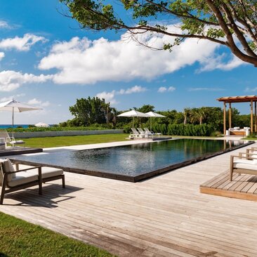 Infinity pool with wooden deck overlooking tropical grounds at Amanyara, Turks and Caicos.