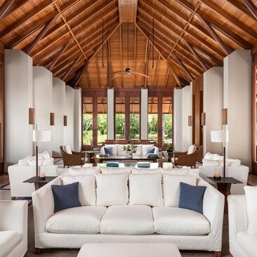Lounge area at Amanyara's four-bedroom villa with wooden vaulted ceiling and ocean views through large windows.