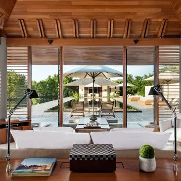 Principal bedroom at Amanyara with wooden ceiling, open doors to terrace, and views toward pool and gardens.