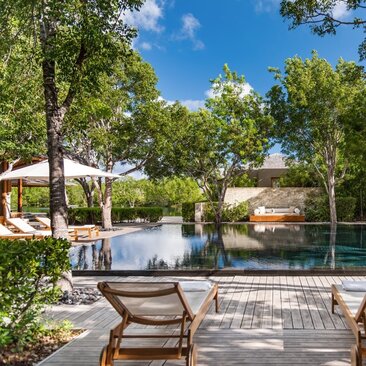 Serenity Villa pool area at Amanyara with loungers overlooking calm waters surrounded by tropical vegetation.