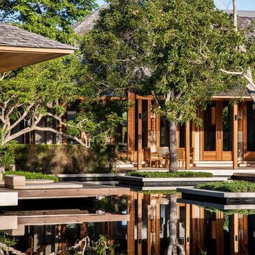 Beach sala at Amanyara with wooden pavilion reflected in still pond, surrounded by lush tropical vegetation.