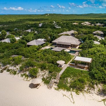 Aerial view of a six-bedroom beach villa at Amanyara, Turks and Caicos, with white sand and turquoise waters.