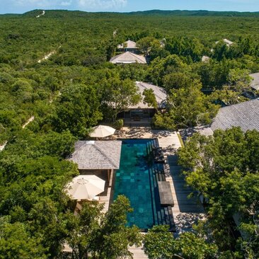 Aerial view of Amanyara's four-bedroom beach villa with infinity pool surrounded by tropical vegetation in Turks and Caicos.