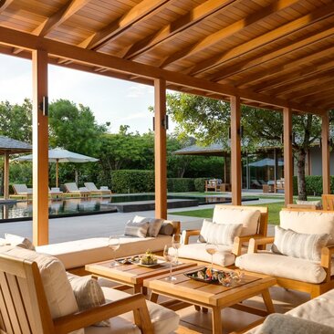 Amanyara villa terrace with wooden pergola, comfortable seating and views over tropical gardens.