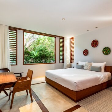 Principal bedroom at Amanyara villa with garden views through sliding doors, wooden furnishings and natural light.