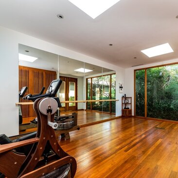 Amanyara villa fitness studio with wooden flooring, exercise equipment and garden views through glass doors.