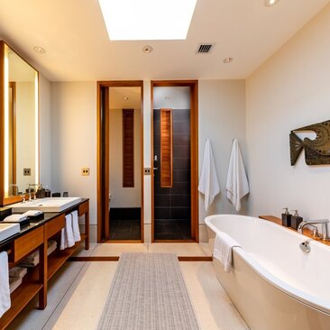 Principal bathroom at Amanyara villa with dual vanity, freestanding bathtub and wooden cabinetry.