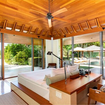 Principal bedroom at Amanyara villa with wooden ceiling, garden views and direct terrace access.
