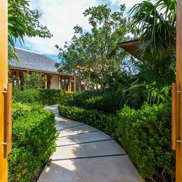 Entrance pathway to a four-bedroom ocean villa at Amanyara, lined with lush tropical greenery and leading towards the main residence.
