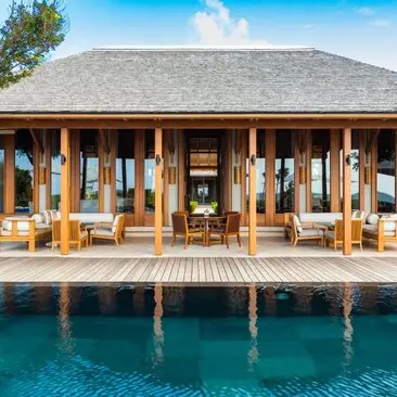 Four-bedroom ocean villa pavilion at Amanyara with wooden columns and deck overlooking turquoise waters.