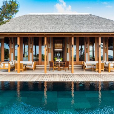 Four-bedroom ocean villa pavilion at Amanyara with wooden columns and deck overlooking turquoise waters.