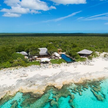 Aerial view of Amanyara villa nestled between turquoise waters and verdant landscape in Turks and Caicos.