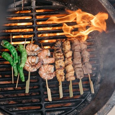 Grilled meat skewers and vegetables on a robata grill at Amanzoe's Nama dining venue.