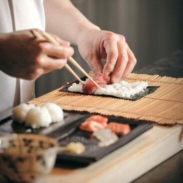 Chef's hands slicing fresh fish at Aman Kyoto's sushi-making experience.