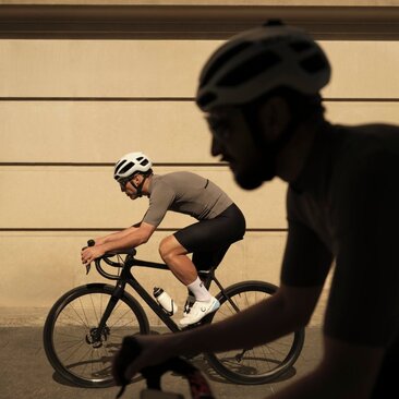 Cyclist riding past a shadow cast on a pale brick wall at Aman New York.