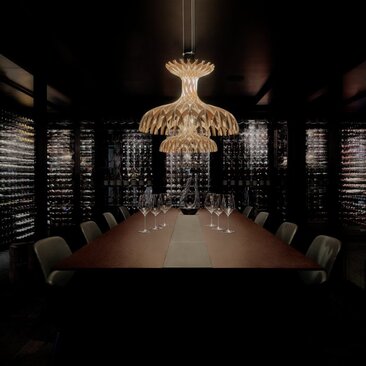 Di Vino Room at Aman Rosa Alpina, Italy, with long dining table and ornate chandelier.