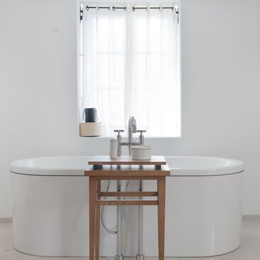 Principal bathroom at Aman Sveti Stefan with oval bathtub, wooden vanity and window overlooking the Adriatic.